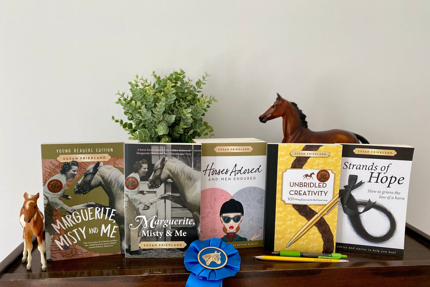 Marguerite, Misty and Me in the young reader and original versions with Horses Adored and Men Endured, Unbridled Creativty and Strands of Hope on top of a bookshelf 